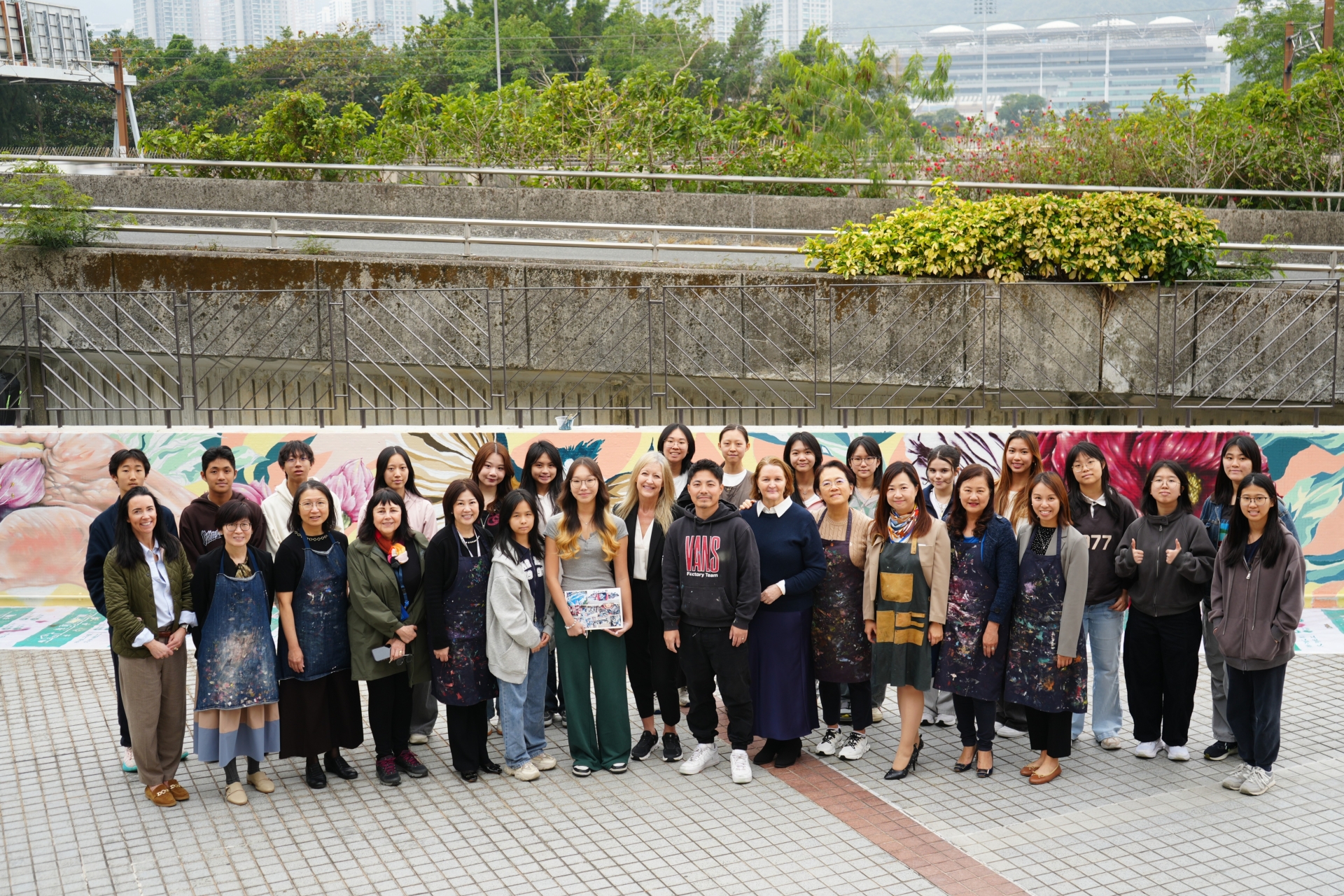 SH collaborates with TAKA (centre, in black sweater) and ESF Sha Tin College on the mural project, showcasing the spirit of inclusion.