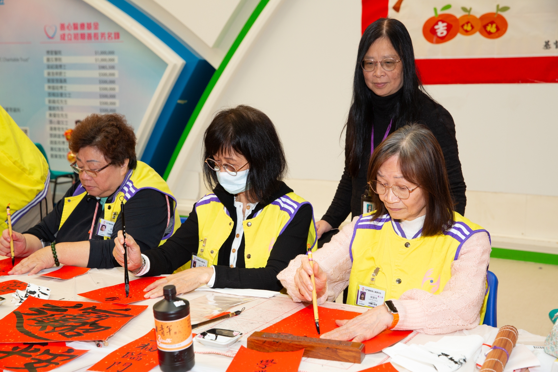 適逢新春佳節，寶珠（右一）與一眾義工於醫院地下大堂一起寫揮春，與眾同樂。
