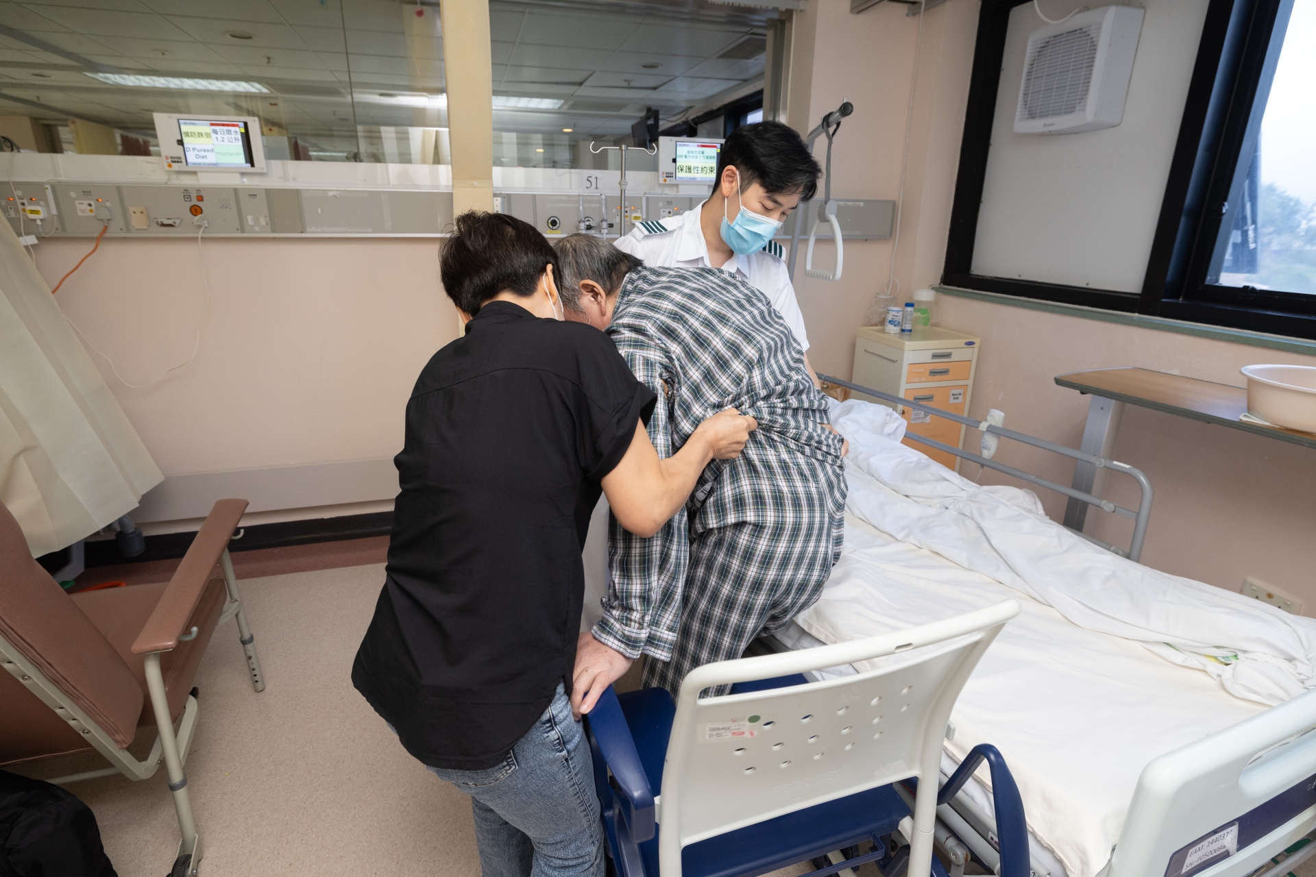 Occupational Therapist Mr Leung (right) teaches Mrs Choi the techniques for transferring the patient to bed.